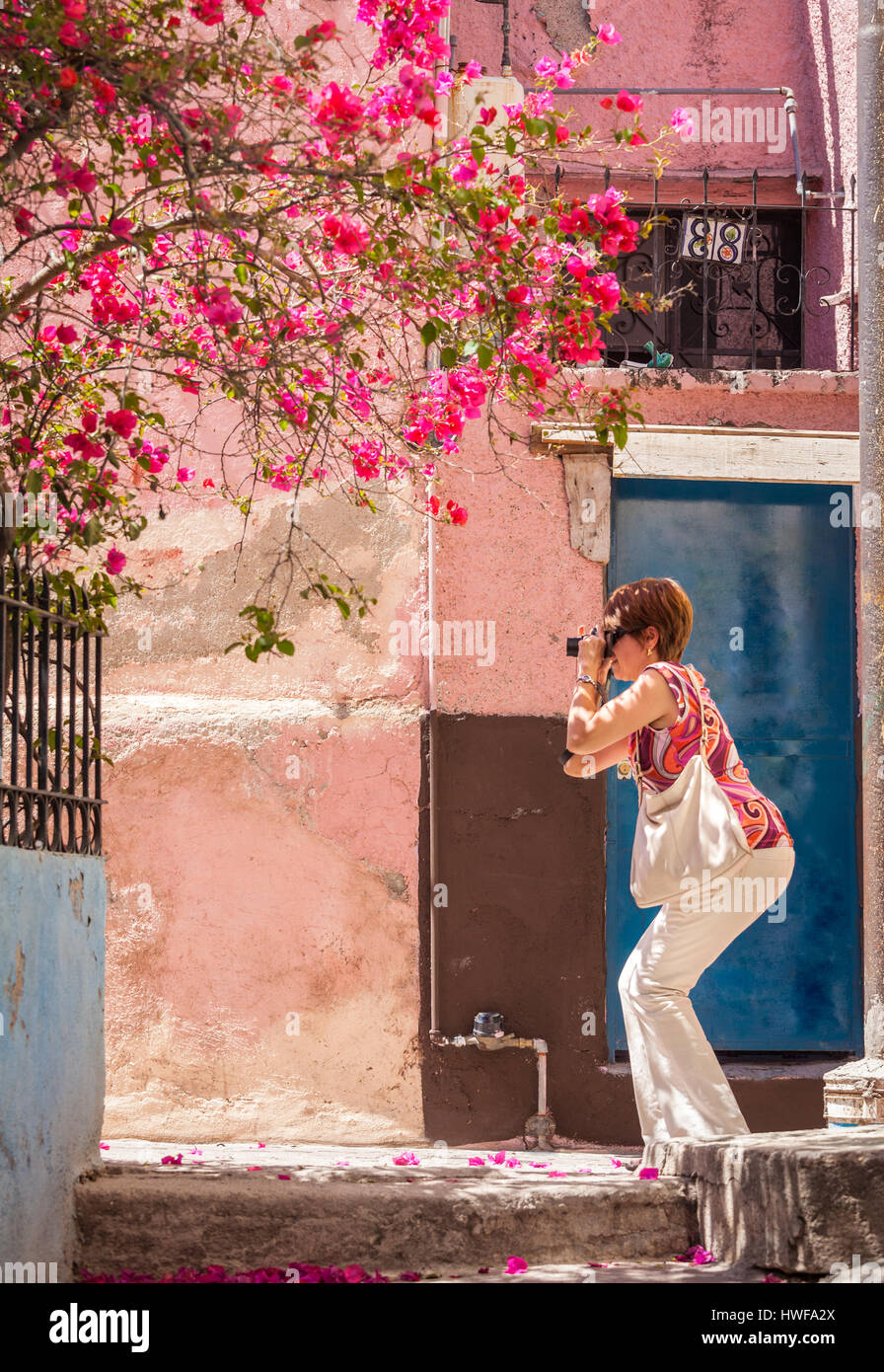 A female tourist shoots for color along  the narrow streets of Guanajuato, Mexico. Stock Photo