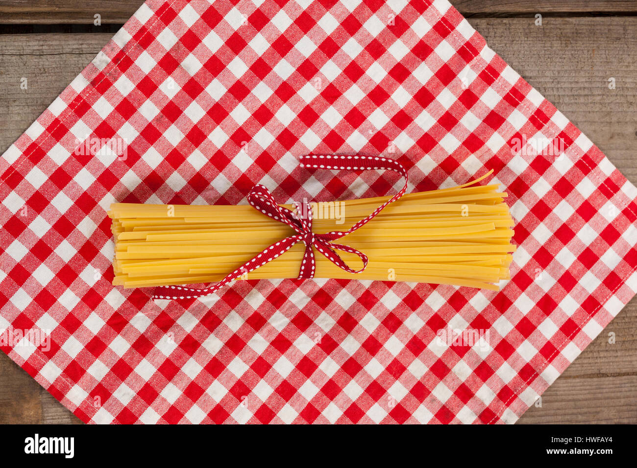 Spaghetti Ruby Ribbons Bundle of raw spaghetti tied with red ribbon on napkin Stock Photo - Alamy
