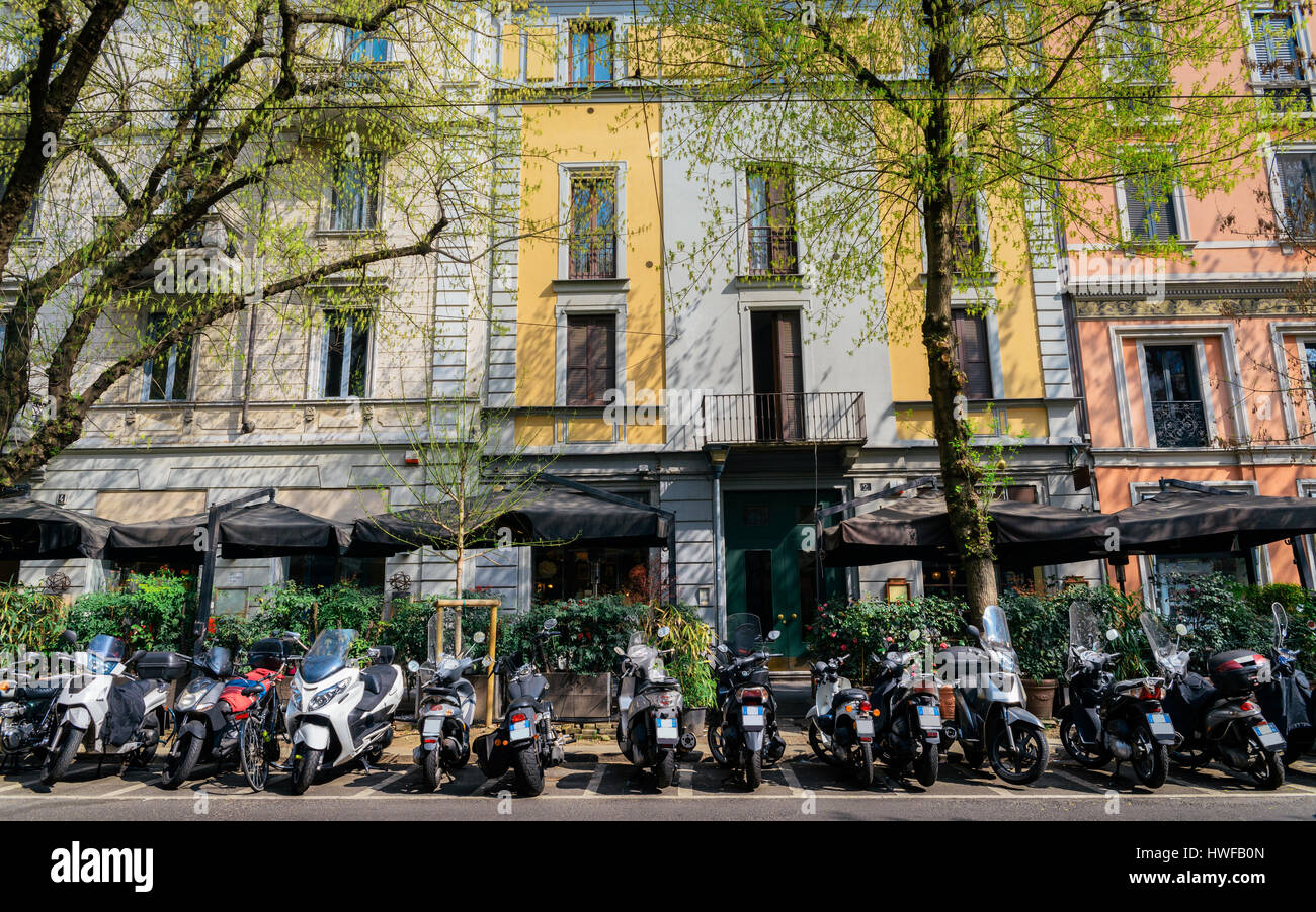 Italian vespas on a busy & colourful Milan street with cafes and restaurants Stock Photo