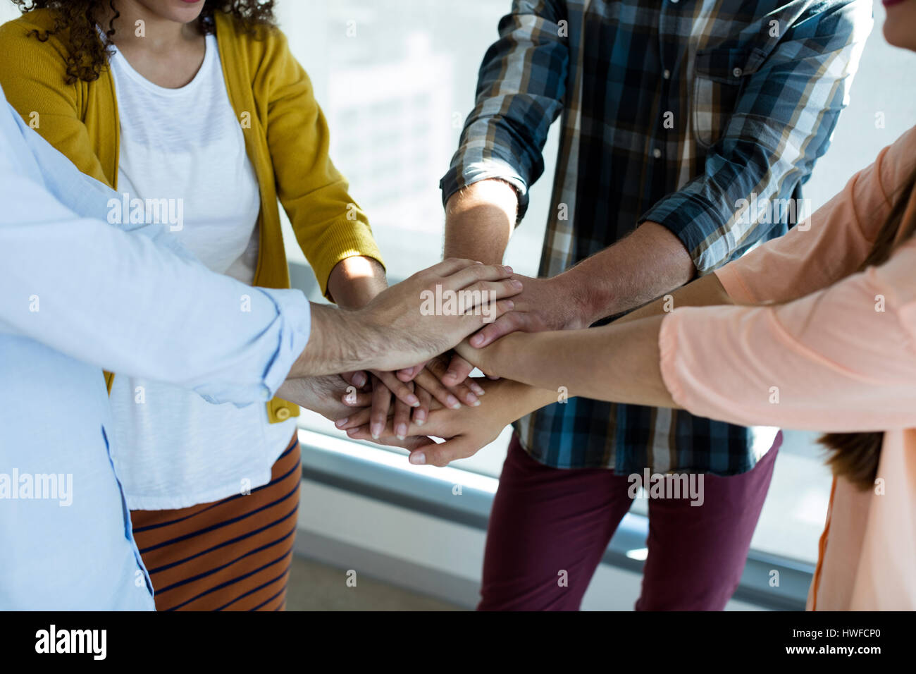 Creative business team stacking hands together in office Stock Photo ...