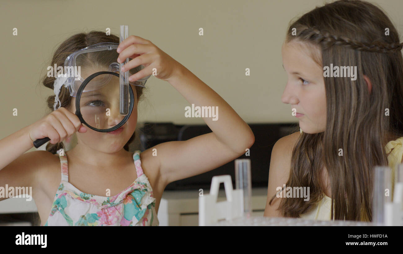 Curious students examining test tube with magnifying glass in science