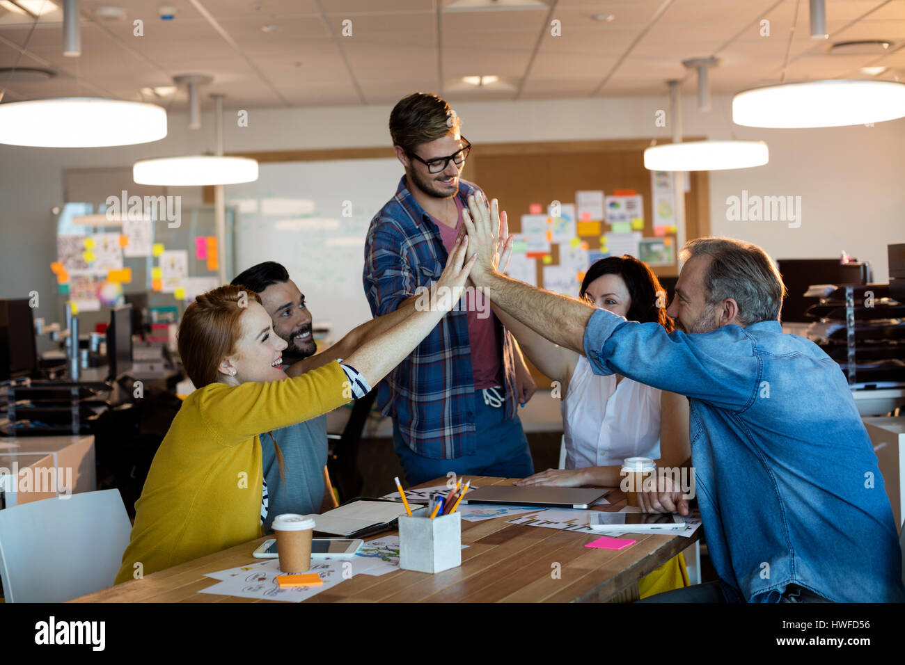 Creative business team giving a high five to each other in office Stock ...