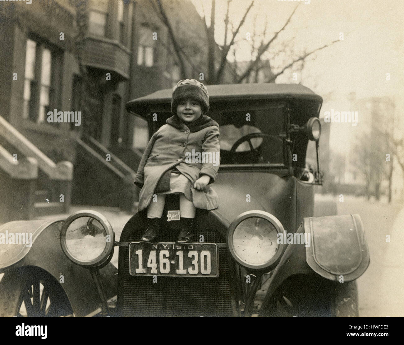 Antique c1918 photograph, little girl on the hood of a 1918 Buick with New York license plate. Location is possibly Brooklyn, New York. See Alamy HWFDD1 for an alternate view of this image. SOURCE: ORIGINAL PHOTOGRAPHIC PRINT. Stock Photo