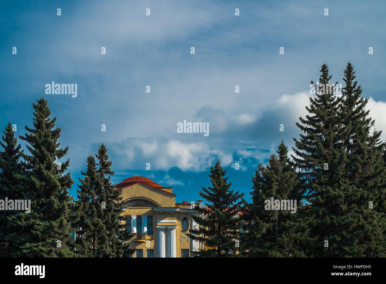 Scenic sunny sky with brights clouds with eastern pines and antic building in Saint  Petersburg botanical garden Stock Photo