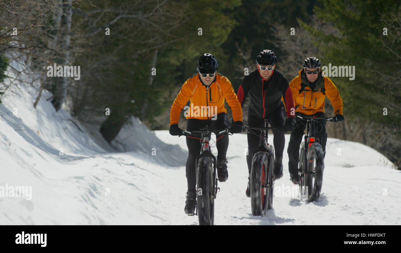 Men riding mountain bikes on remote snowy hillside Stock Photo