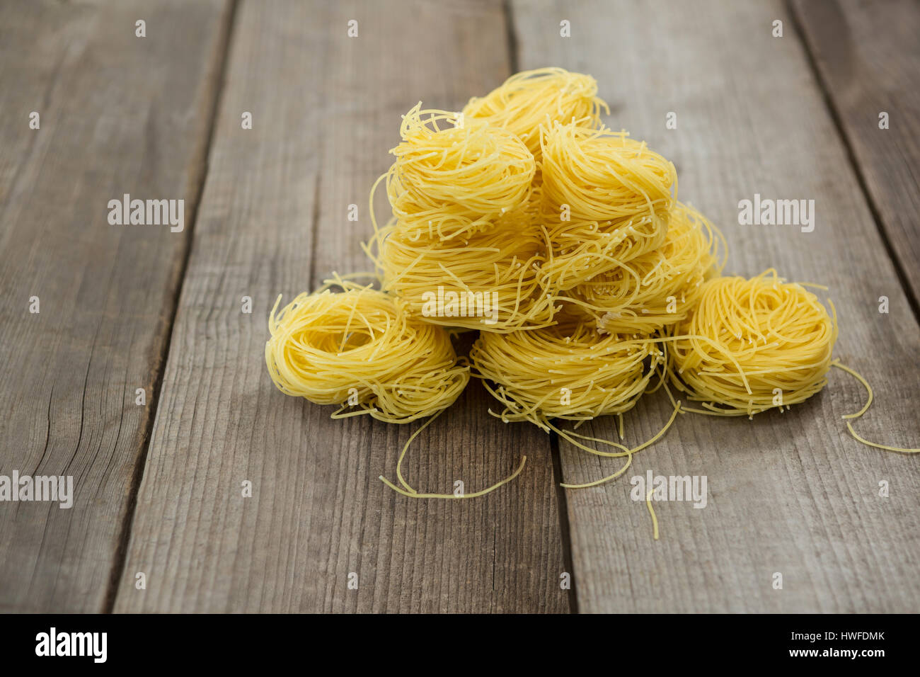 Pile of capellini pasta on wooden surface Stock Photo Alamy
