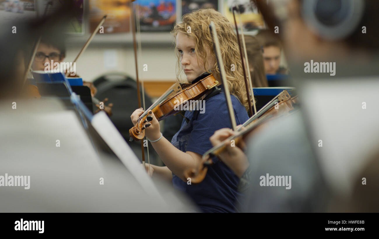 Selective focus view of serious teenage girl musician playing violin in band class Stock Photo