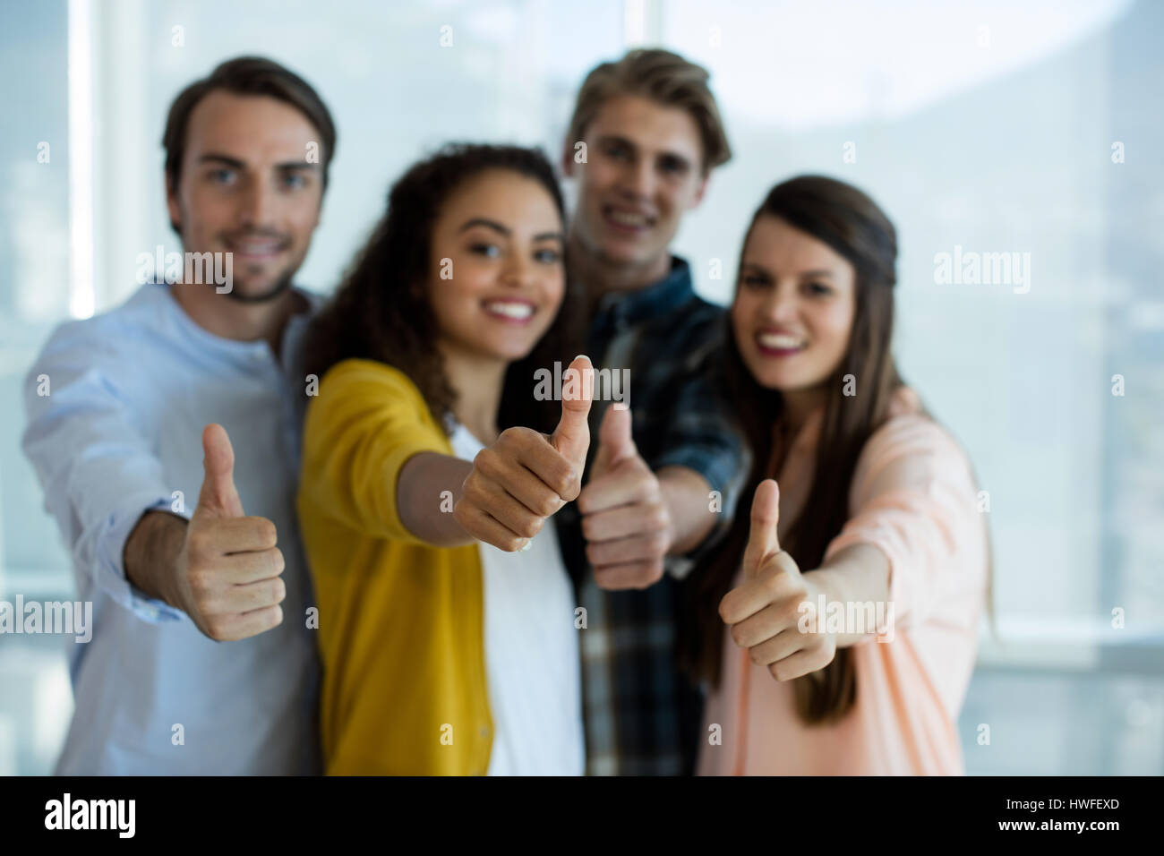 Portrait of smiling creative business team showing thumbs up in office ...