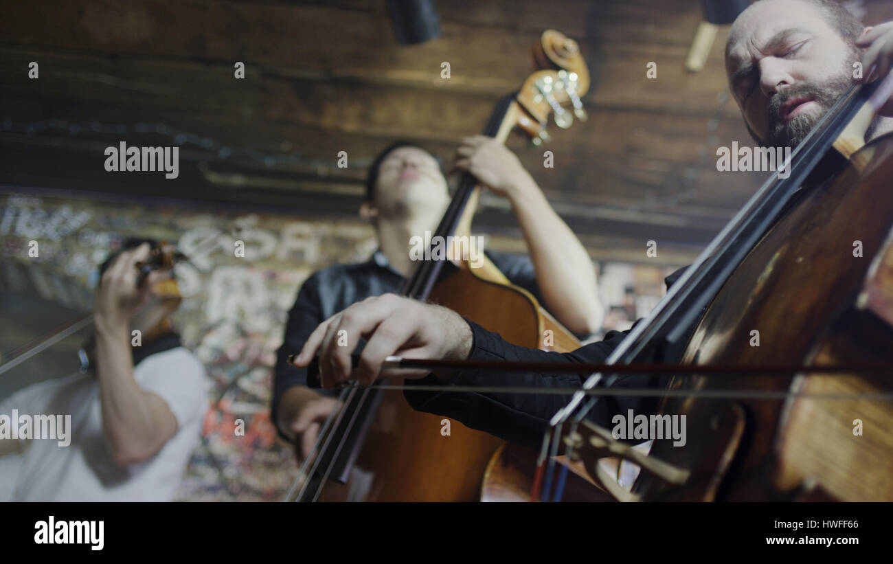 Low angle view of serious musicians playing violin in band in cafe Stock Photo