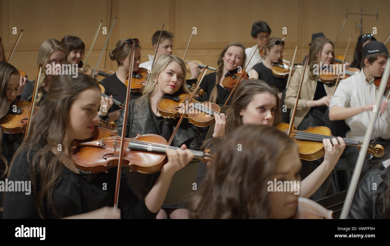 Selective focus view of student musicians playing instruments in orchestra recital Stock Photo