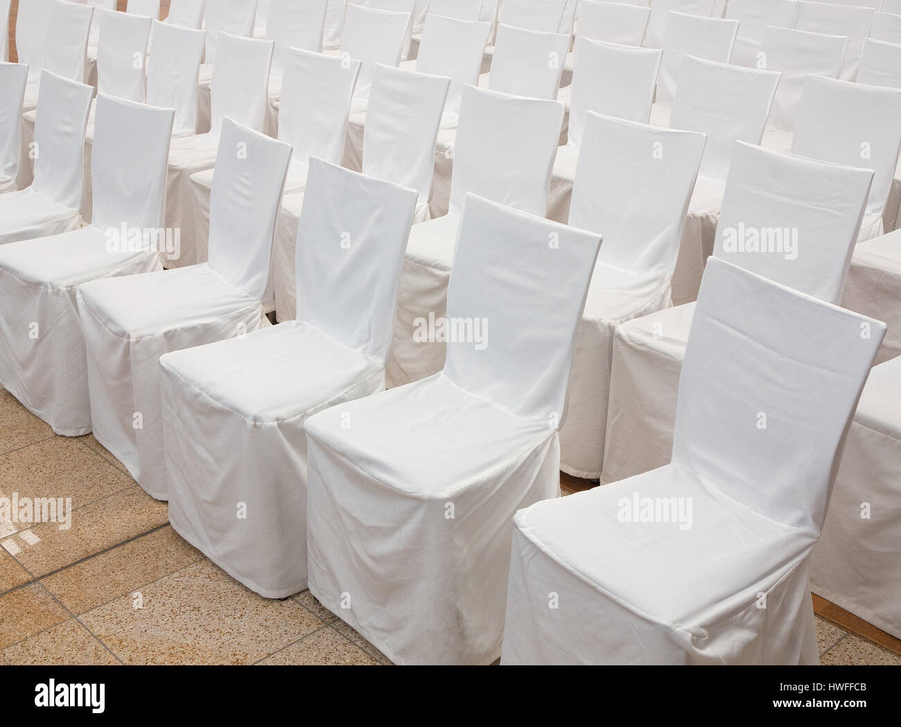 Row of chairs with white fabric covers Stock Photo