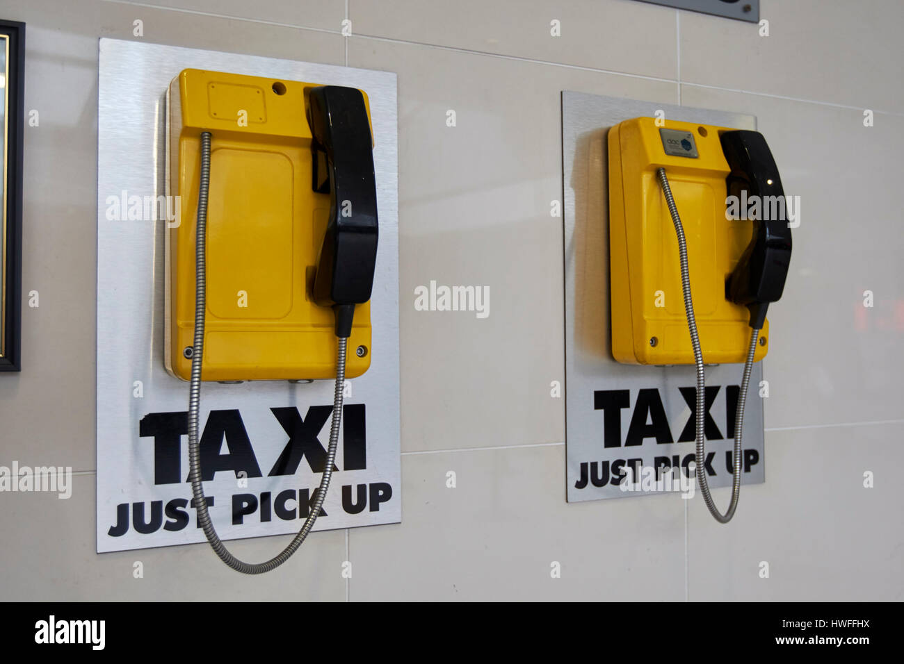 yellow dedicated taxi phone pickup lines in transport hub Belfast Northern Ireland Stock Photo