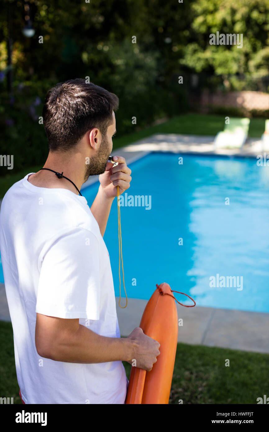 Lifeguard blowing whistle at poolside on a sunny day Stock Photo Alamy