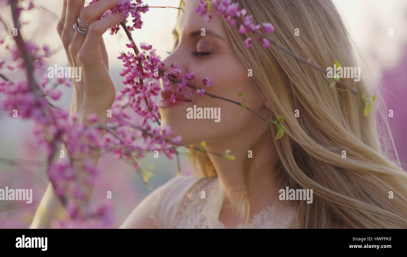 Selective focus view of woman smelling flowering tree branches in park Stock Photo