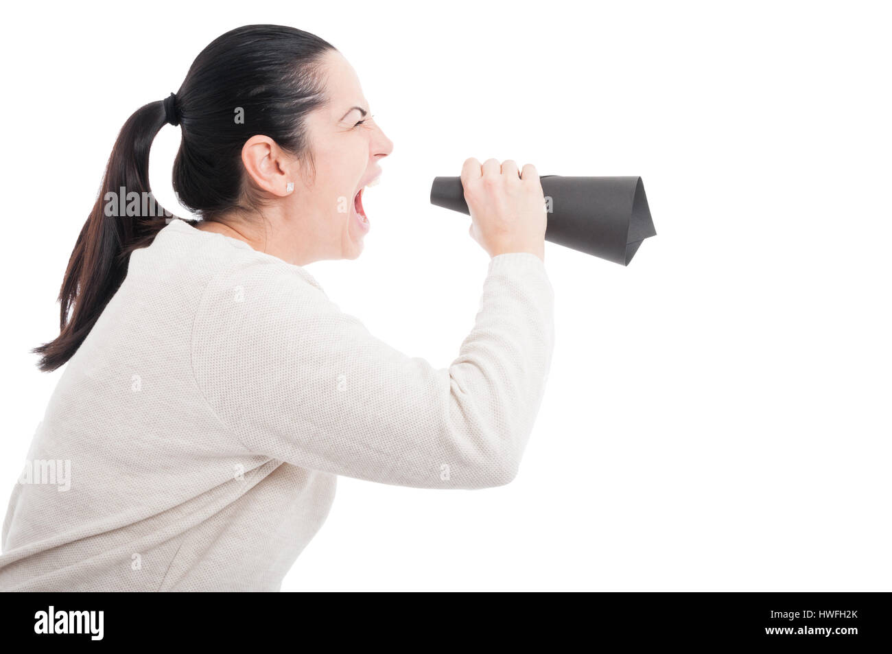 Young girl screaming with rage in a paper loudspeaker on white background Stock Photo