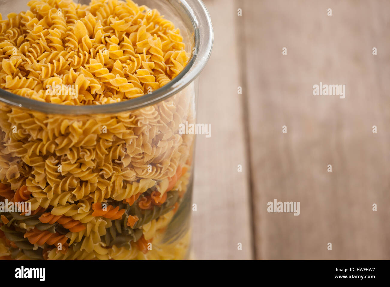 Girandole pasta in a glass container on wooden table Stock Photo