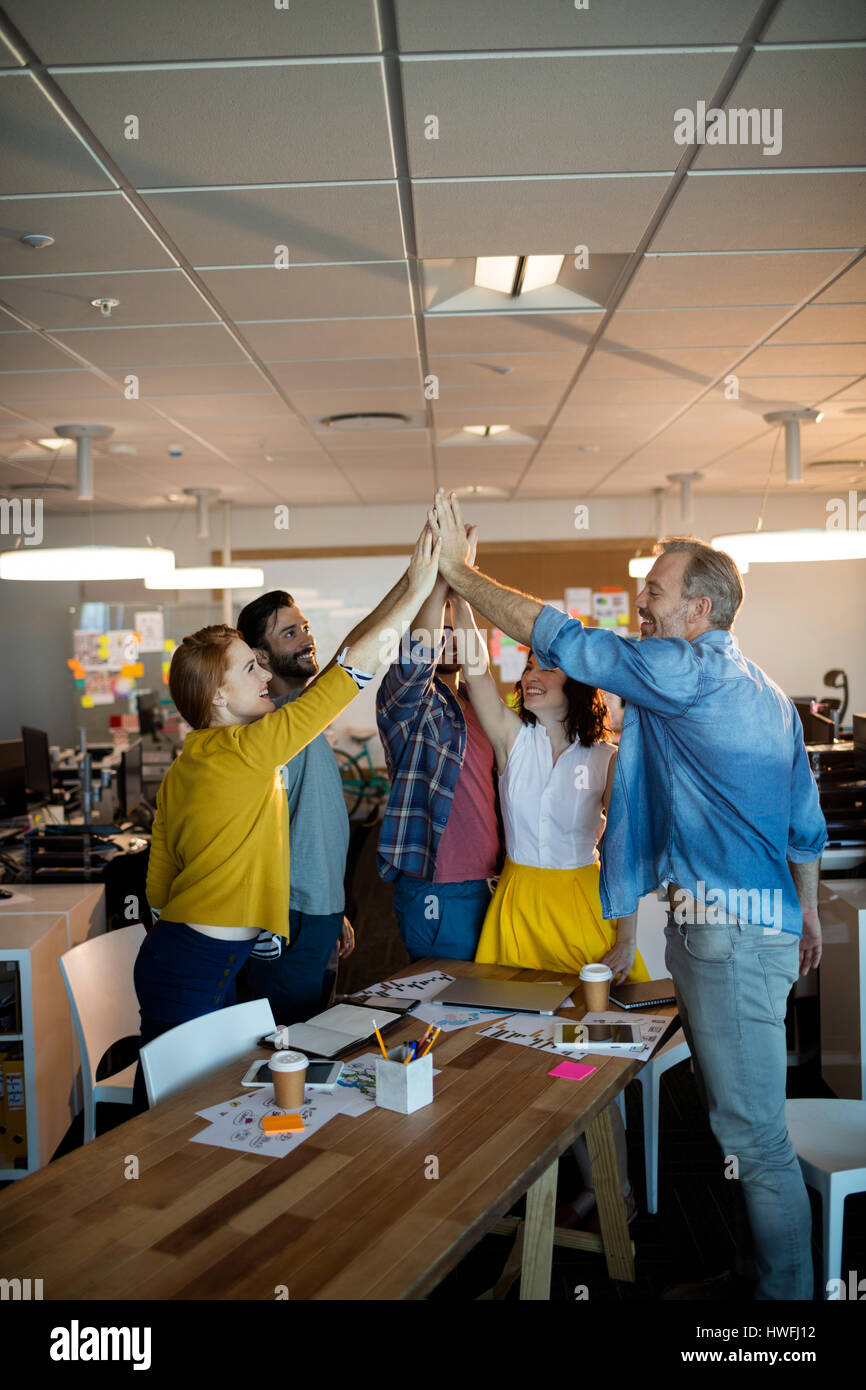 Creative business team giving a high five to each other in office Stock ...