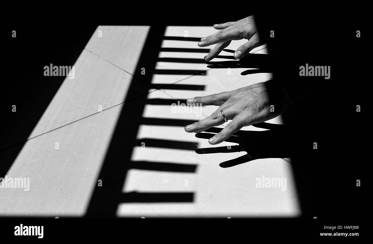 Hands playing the Light and Shadow piano on the ground B&W Stock Photo