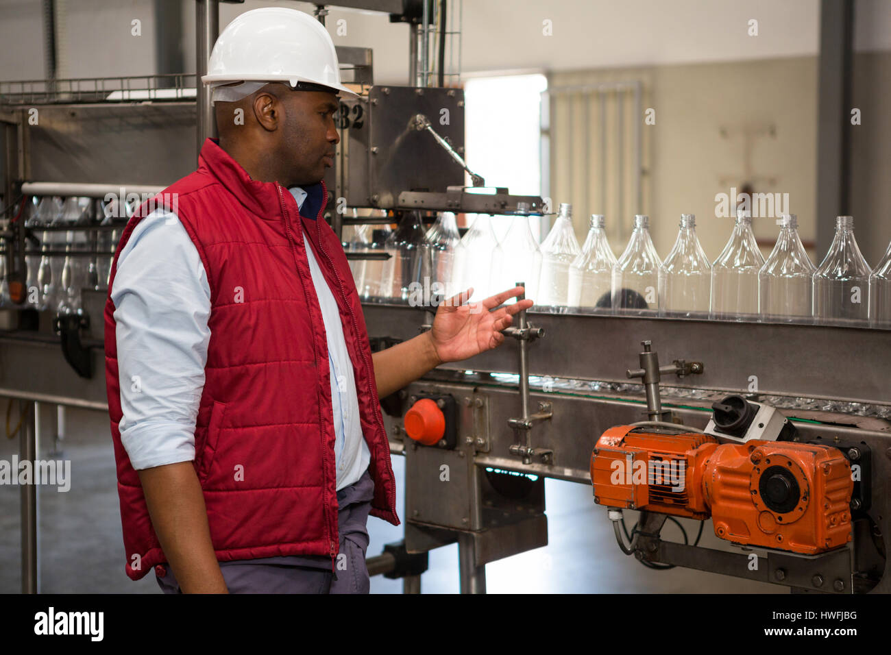 Confident male operator monitoring bottles on production line in juice factory Stock Photo