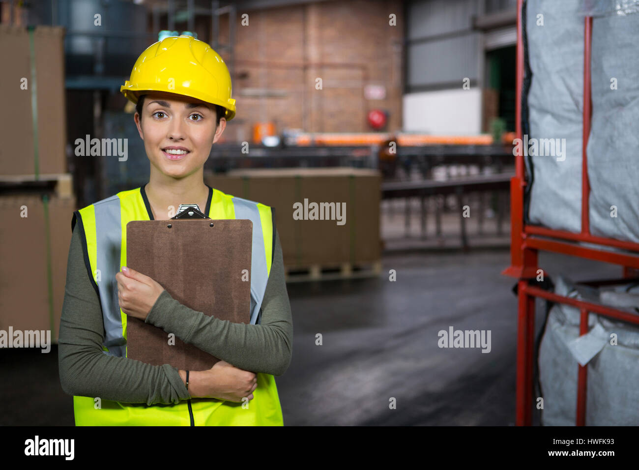 Portrait of young female worker holding clipboard in warehouse Stock Photo