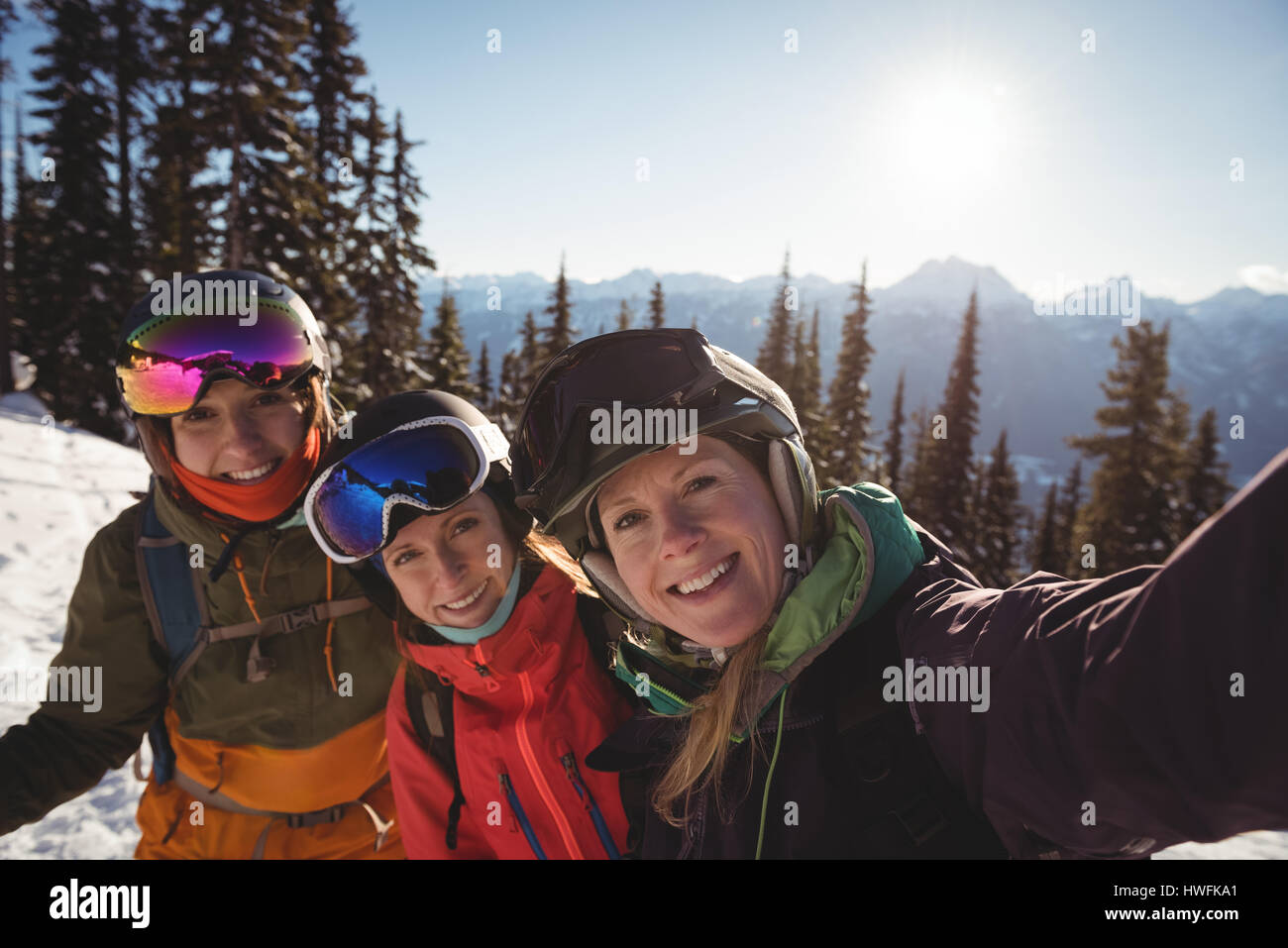 Portrait of three female skiers standing together on snow covered mountain Stock Photo