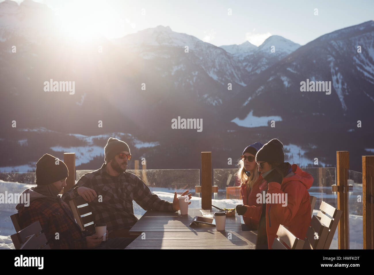 Skiers interacting with each other while having cup of coffee in ski resort Stock Photo