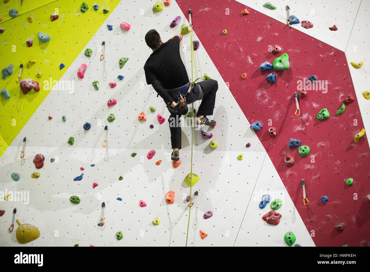 Man practicing rock climbing on artificial climbing wall in gym Stock Photo