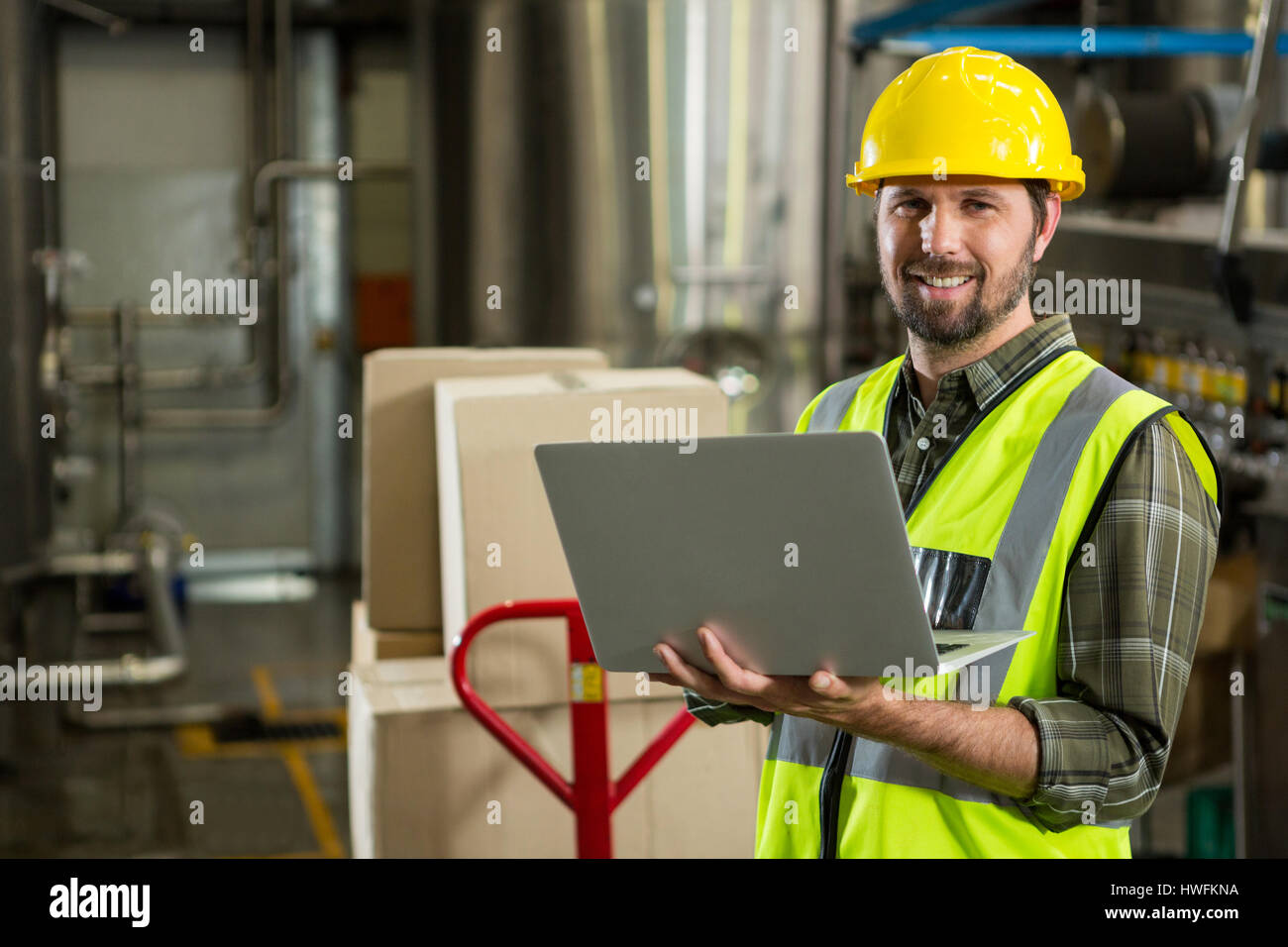 Portrait of smiling male worker using laptop in distribution warehouse Stock Photo