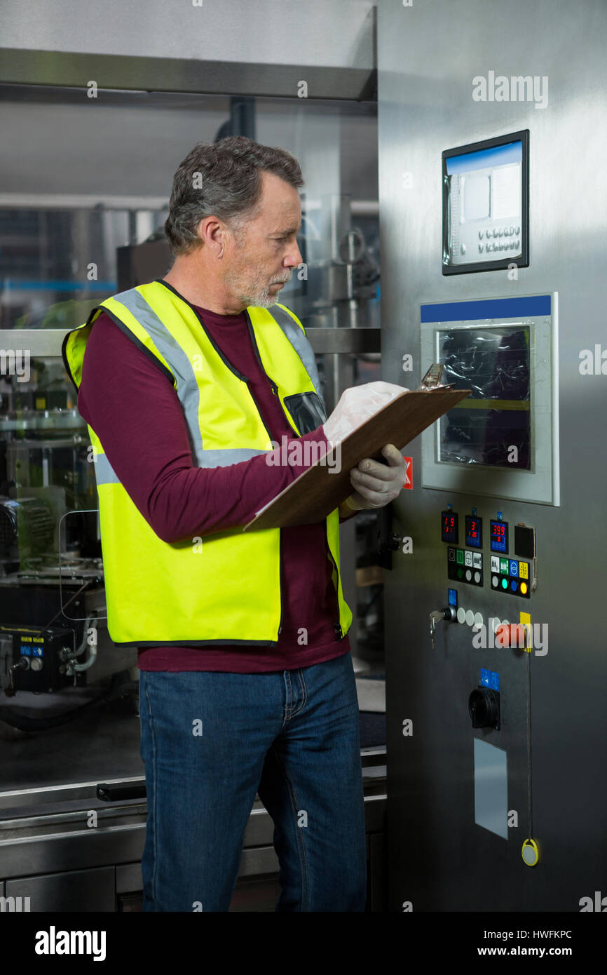 Manual worker analyzing machinery in factory Stock Photo
