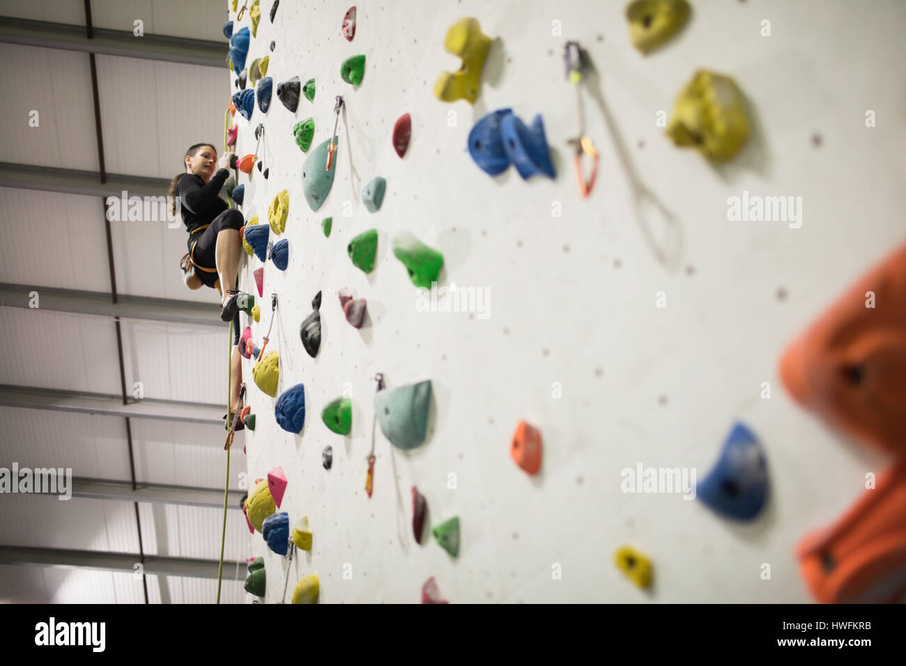 Woman practicing rock climbing on artificial climbing wall in gym Stock Photo