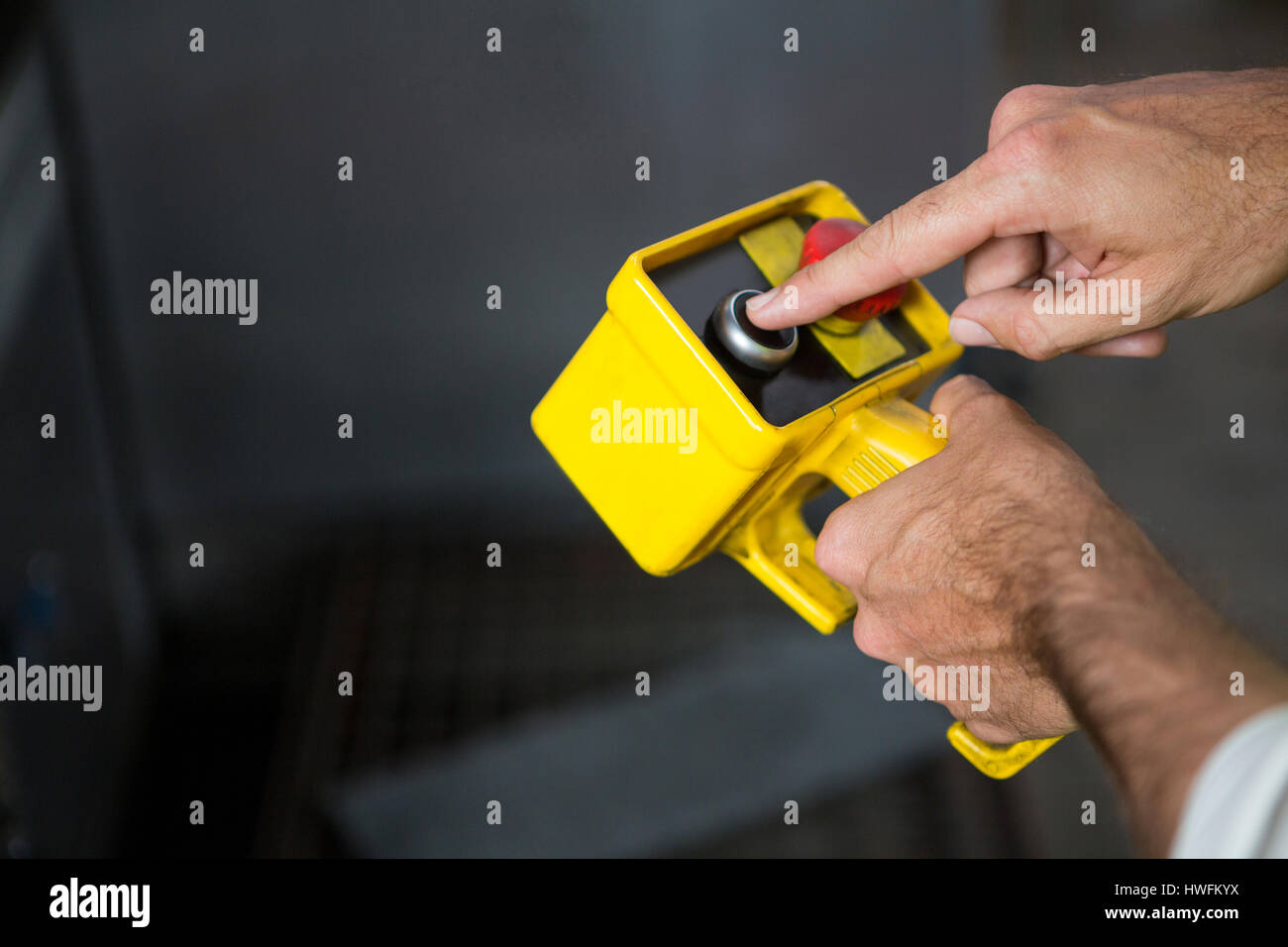 Cropped hands of male worker using yellow tool in factory Stock Photo