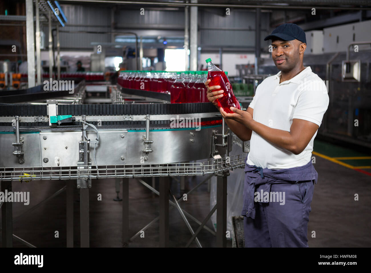 Portrait of young worker inspecting juice bottle at factory Stock Photo