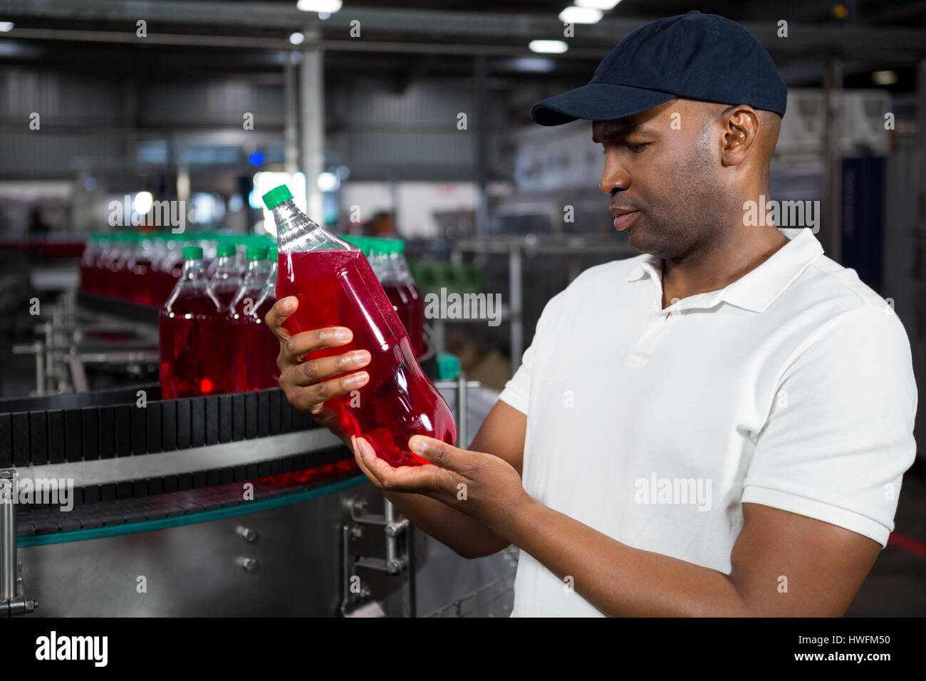 Young male worker inspecting juice bottle in factory Stock Photo