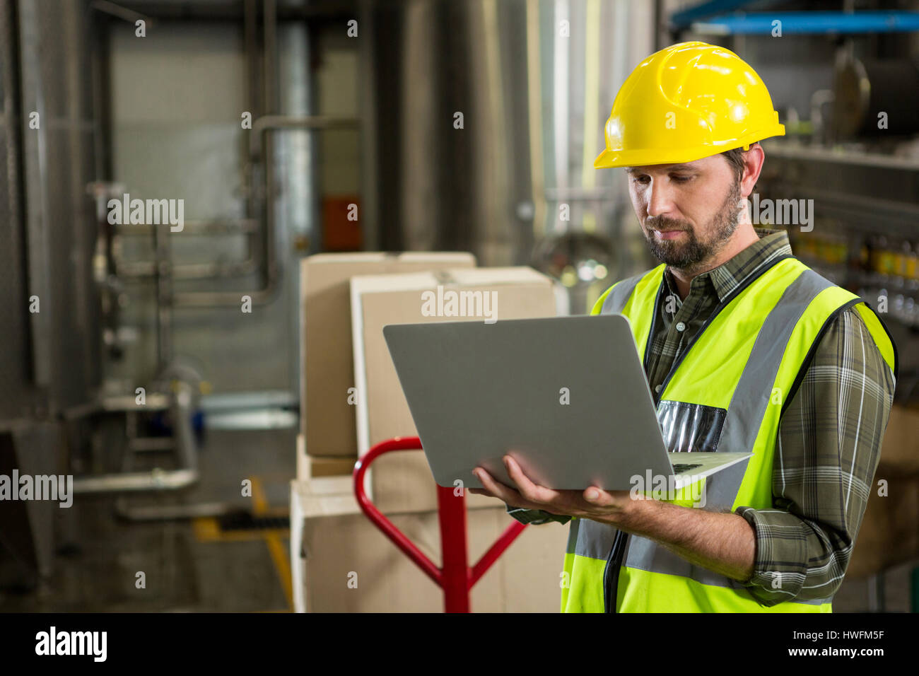 Serious male worker using laptop in distribution warehouse Stock Photo