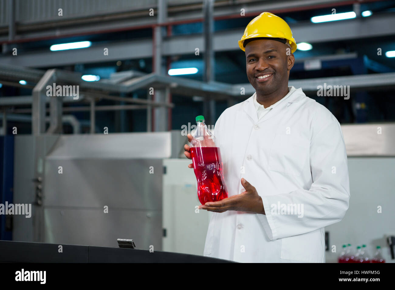 Portrait of male worker showing juice bottle in factory Stock Photo
