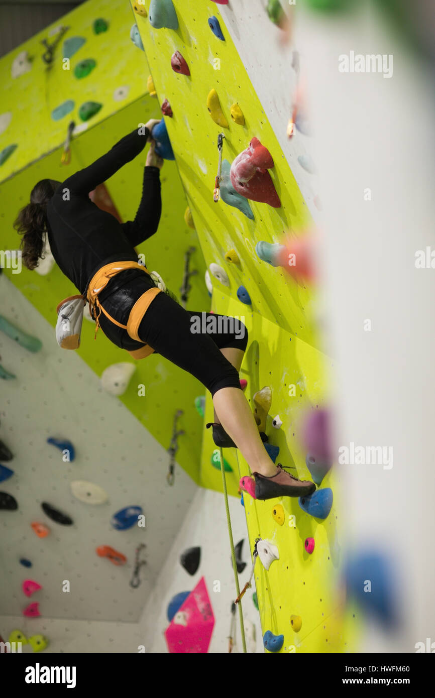 Woman practicing rock climbing on artificial climbing wall in gym Stock Photo