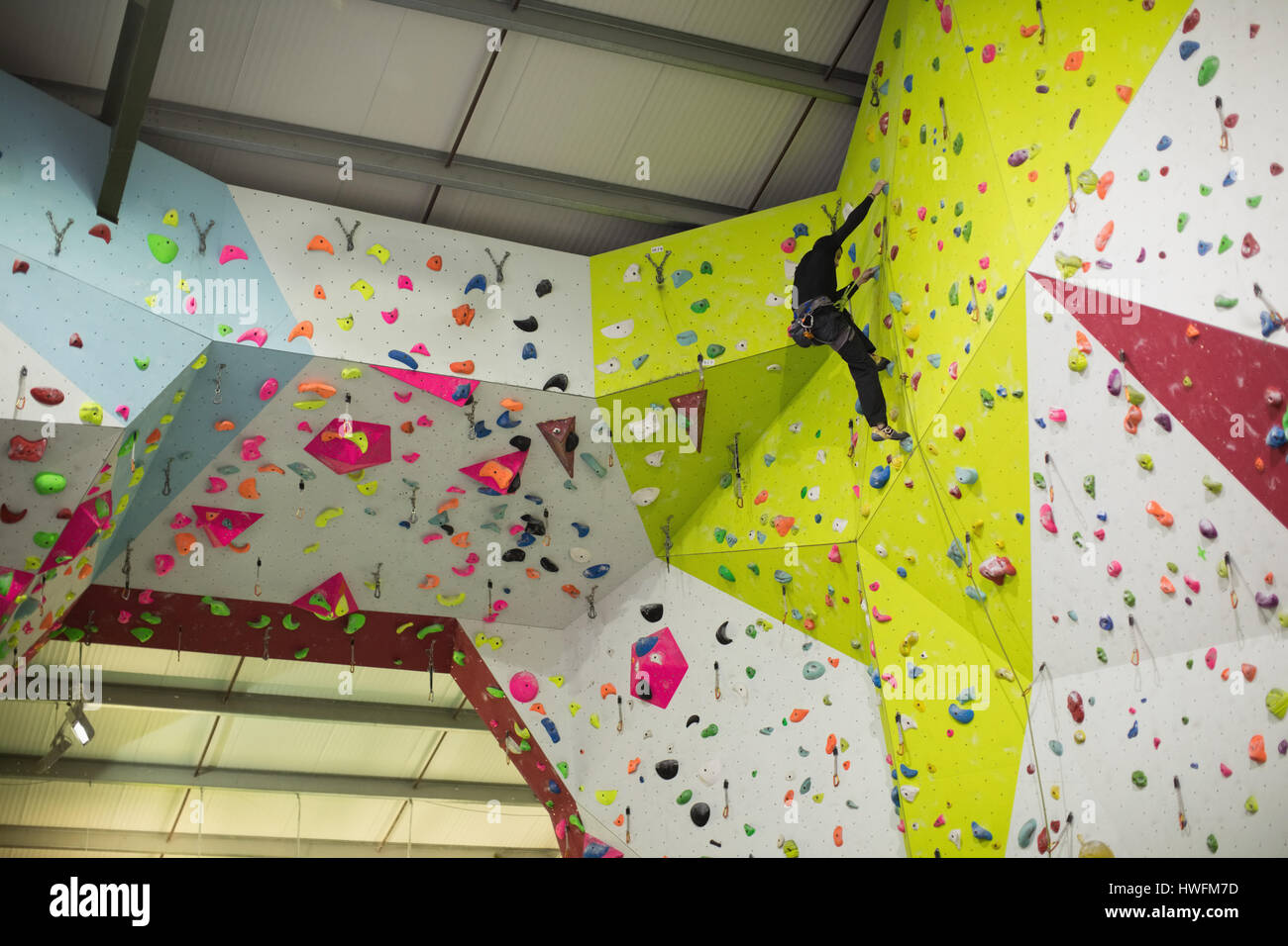 Man practicing rock climbing on artificial climbing wall in gym Stock Photo