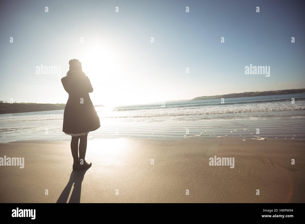 Rear view of woman standing on beach during day Stock Photo - Alamy
