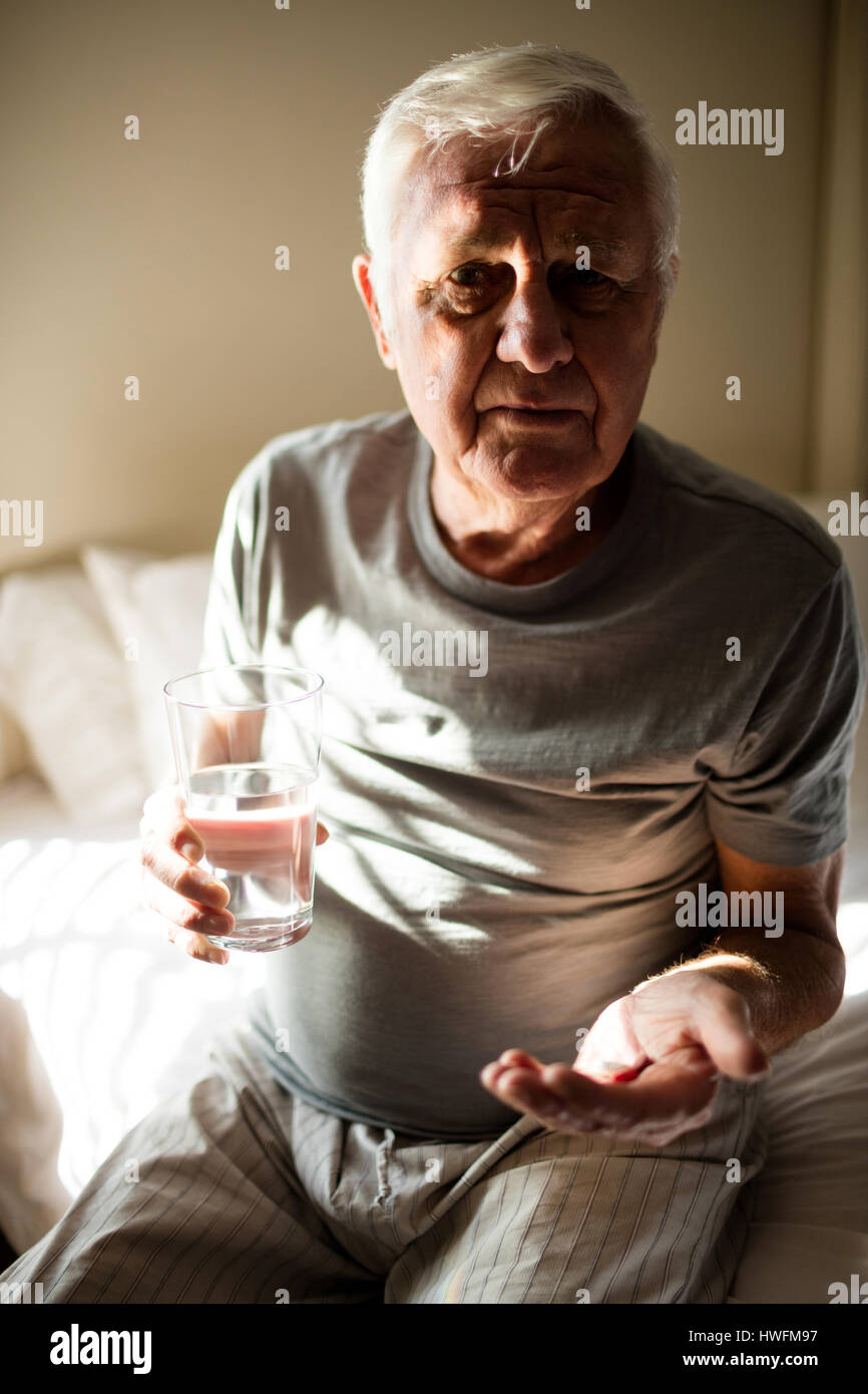 Senior man taking medicine in the bedroom at home Stock Photo