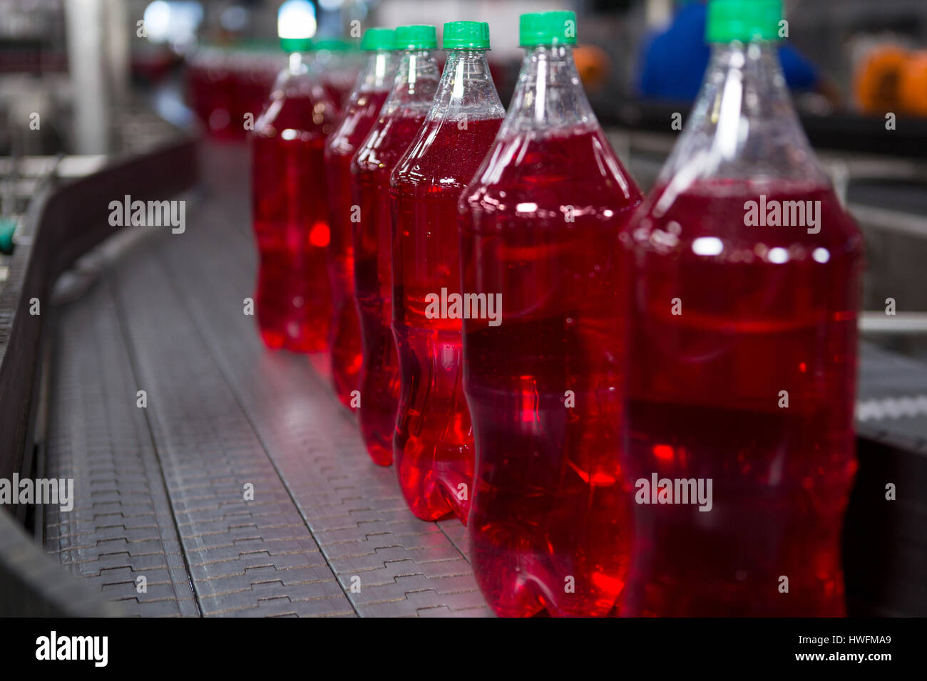 Filled red juice bottles on production line in factory Stock Photo