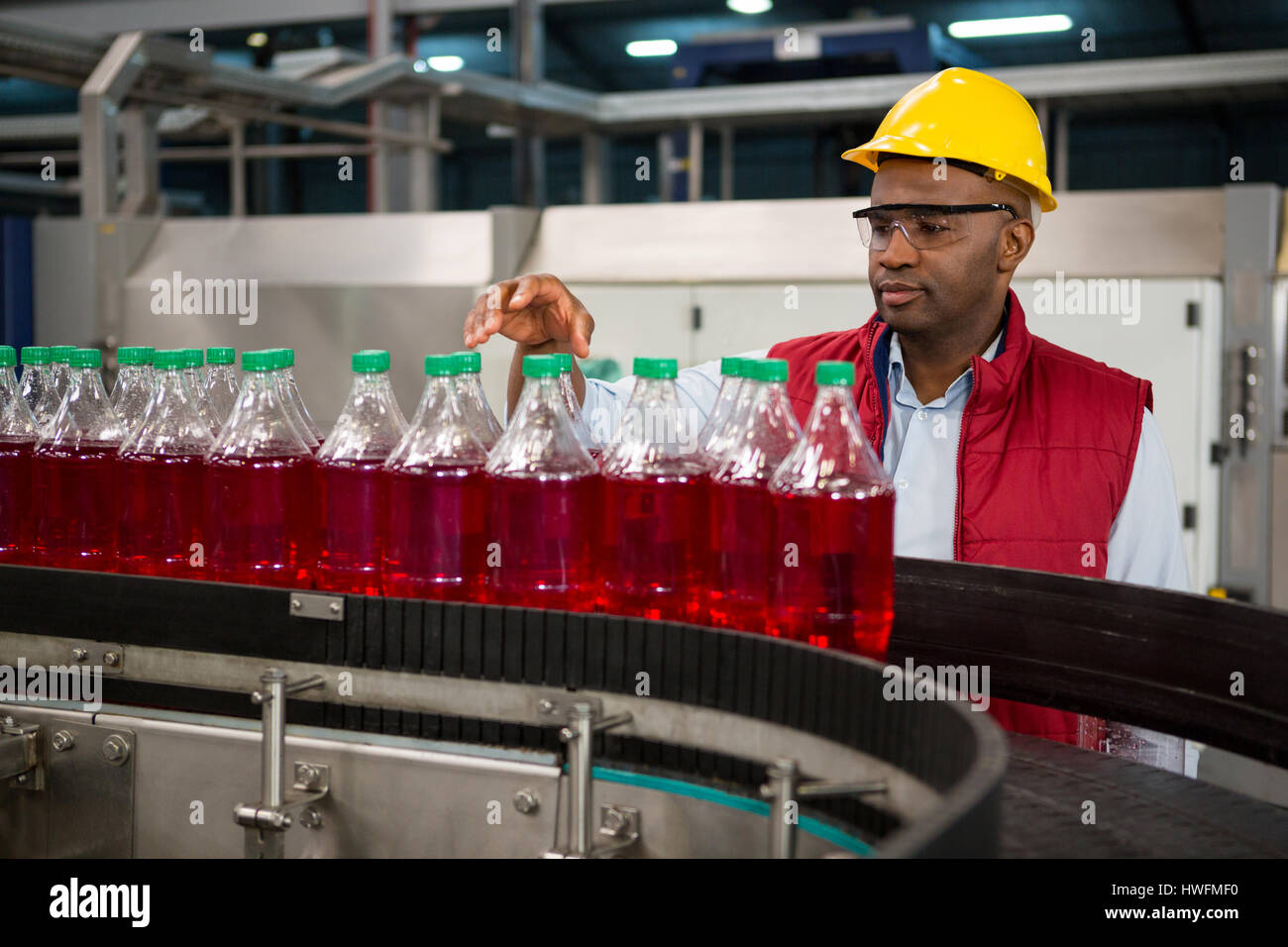 Confident male employee inspecting bottles in juice factory Stock Photo