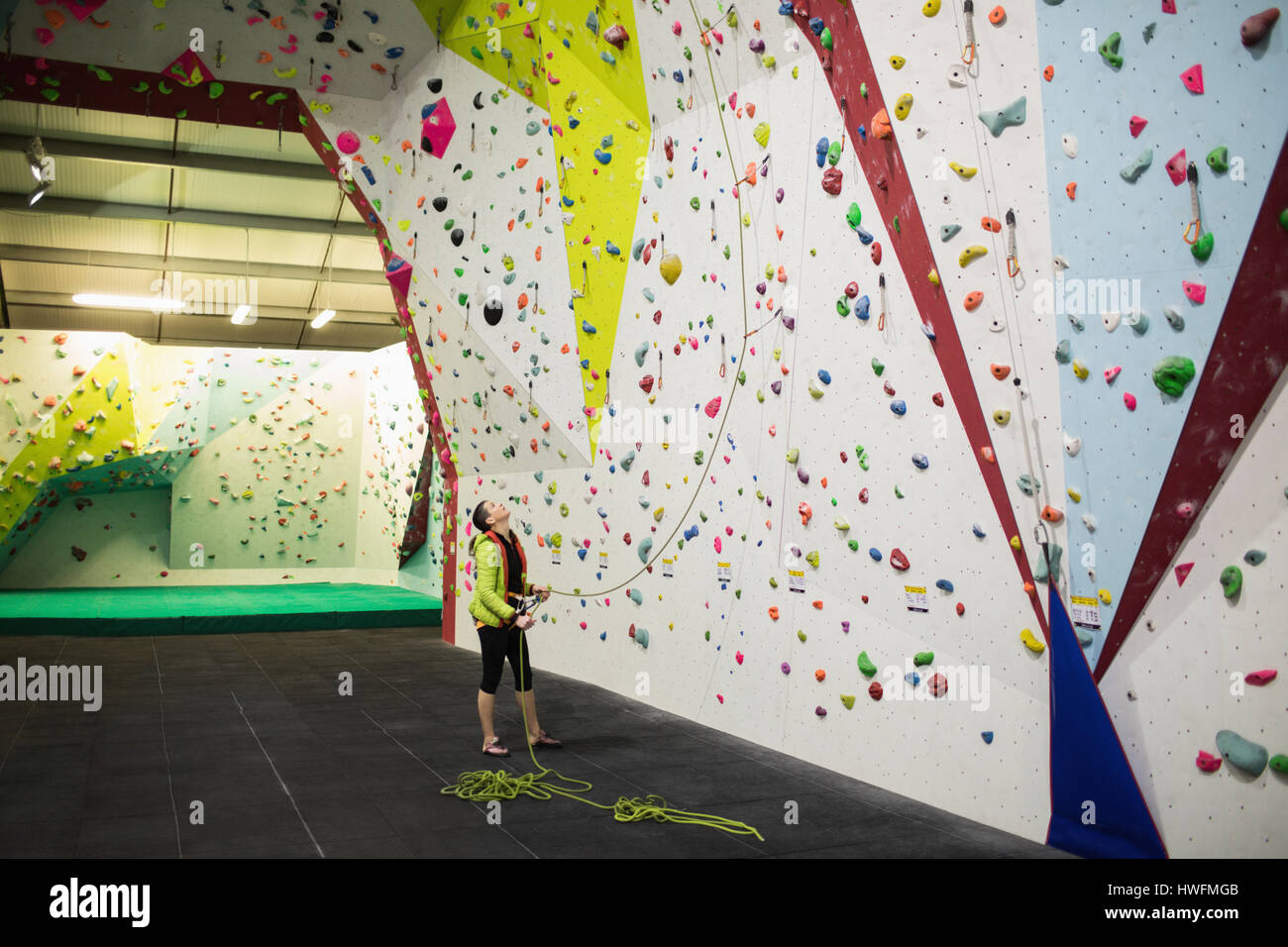 Trainer holding the rope near artificial climbing wall in gym Stock Photo