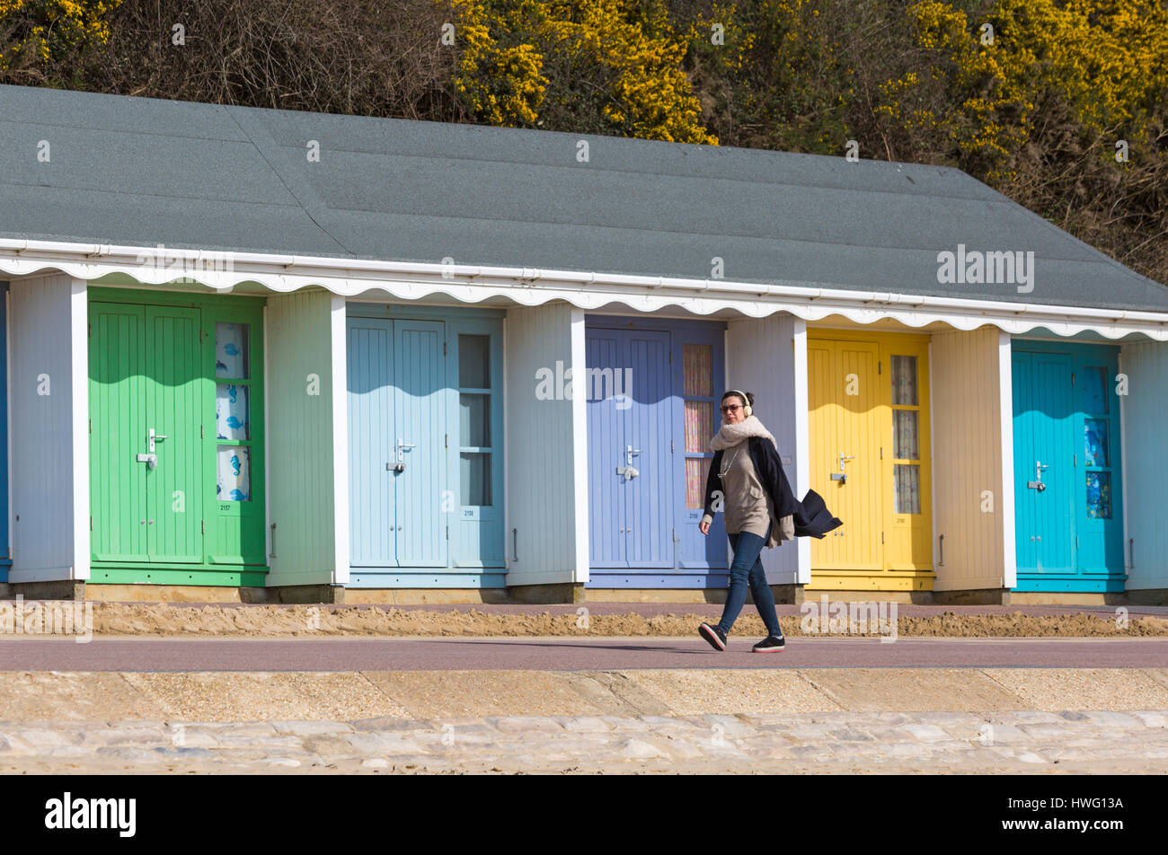 Bournemouth, Dorset, UK. 21st Mar, 2017. UK weather: Bournemouth enjoys a lovely sunny day as visitors head to the seaside to make the most of the sunshine at Bournemouth beaches. Woman wearing headphones walking along the promenade past beach huts  Credit: Carolyn Jenkins/Alamy Live News Stock Photo