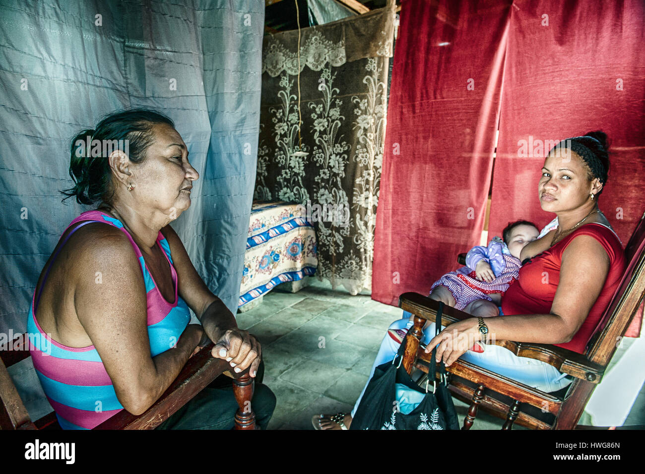 Mother, daughter and baby inside an house partially destroyed by the fury of the hurricane Matthew in Baracoa, Cuba Stock Photo