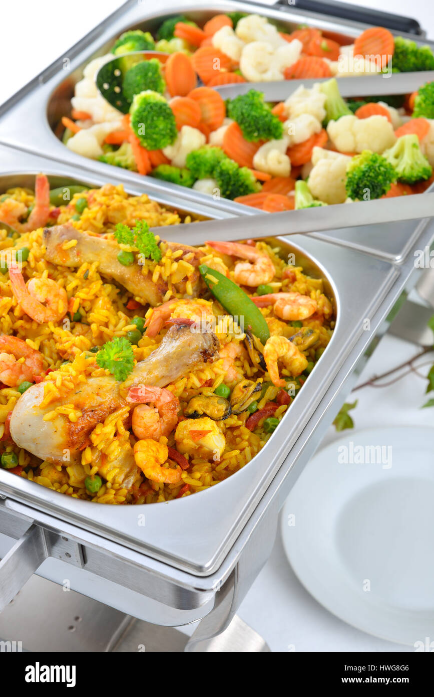 Warm buffet with Spanish paella and mixed buttered vegetables served in a chafing dish Stock Photo