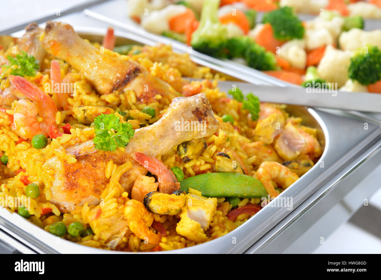 Warm buffet with Spanish paella and mixed buttered vegetables served in a chafing dish Stock Photo