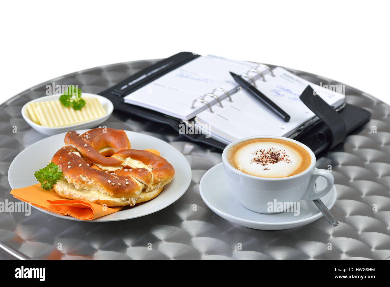 Business break with a pretzel, butter and a cup of cappuccino; a personal organizer in the background Stock Photo