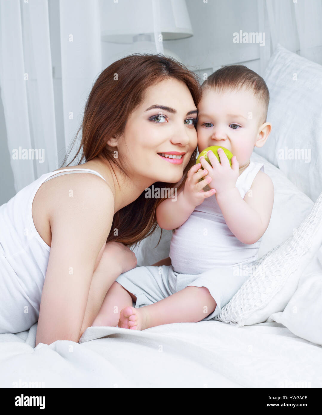happy beautiful mother with her one year old son in bed at home Stock