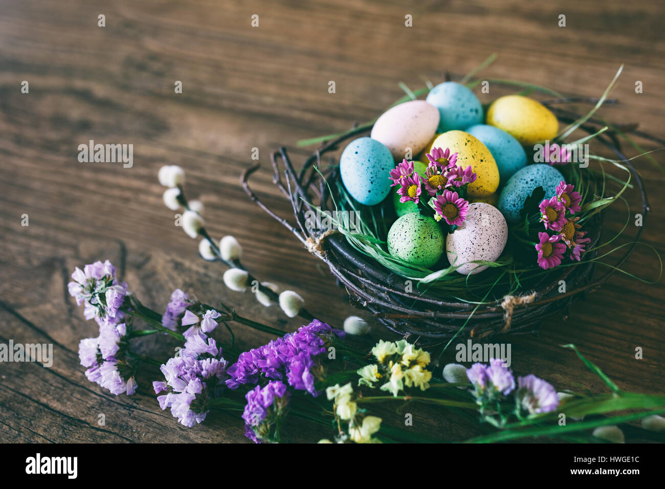 Easter background. Beautiful colorful eggs in nest with spring flowers ...