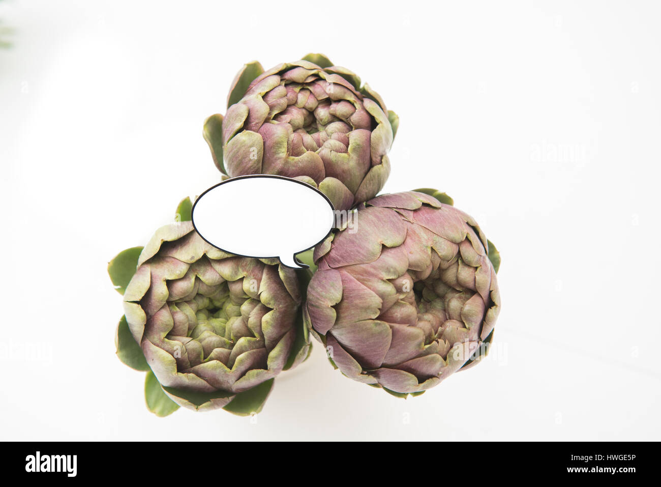 Bunch of fresh raw artichokes and  funny comic style label for market price on white background Stock Photo